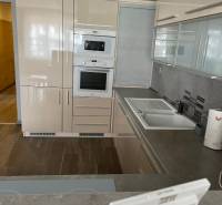 A kitchen in a 4-room apartment with a corner-positioned kitchen unit and a floor with a wooden decor.