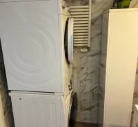 Washer-dryer in the bathroom of a 4-room apartment, marble tiles on the walls.