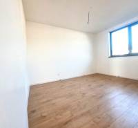 An empty room with a wood-patterned floor and a large window in a family house.