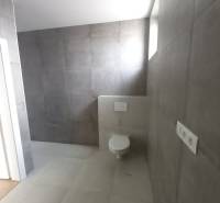 Bathroom in a family house with gray decor tiles and a wall-mounted toilet.