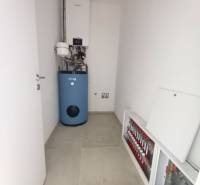 Technical room in a family house with a gas boiler and underfloor heating distributors.