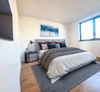 Bedroom in a family house with a bed, painting, TV, and floor with wooden decor.