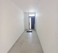 A narrow white hallway with tiles and entrance doors in a family house.