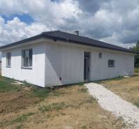 A family house in Galanta with a white exterior on a grassy plot under a cloudy sky.