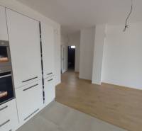 The kitchen area of a family house with white cabinets and a floor with a wooden decor.