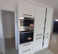 White kitchen unit with integrated appliances in a family house, with a wooden decor floor.