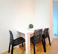 Dining area in a 2-room apartment with black chairs and a white table.