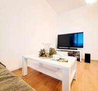 Living room in a two-room apartment with a wooden decor floor and a white table.