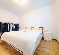 Bright bedroom with a wardrobe and a bed, complemented by a wooden decor floor.