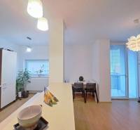 Kitchen and dining area with wood-patterned flooring in a 2-room apartment.