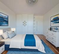 A bright bedroom with blue accents and wood-patterned flooring in a 2-room apartment.