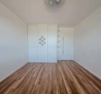 A room with a wooden decor floor, a built-in wardrobe, and shelves in a 2-room apartment.