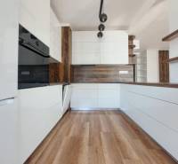 A kitchen in a 2-room apartment with white cabinets and a wood-patterned floor.