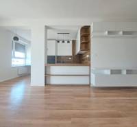 Kitchen area in a 2-room apartment with a wood-patterned floor and white cabinets.