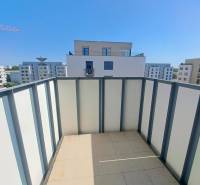 The balcony of a 2-room apartment in Galanta with a view of modern buildings and a blue sky.