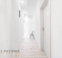 A bright hallway with a wooden floor and a chair in the office.