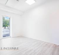 An empty office with a wooden floor and a large window.