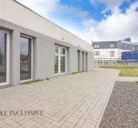 On Vajanského Street, next to commercial spaces with modern architecture and paved sidewalks.