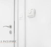 White wall with a thermostat and a handle in the office.