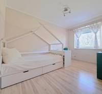 A children's room in a family house with a bed shaped like a house and a floor with a wooden decor.