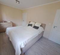 Bedroom in a family house with a bed, dresser, and wooden decor flooring.