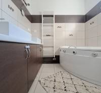 A bathroom in a family house with a bathtub, a sink, a white radiator, and tiles.