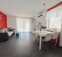 Living room in a family house with a red wall, gray tiles, and white furniture.