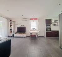Living room with TV, kitchen, and dining table, floor with wooden decor.