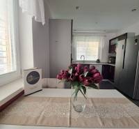 A kitchen in a family house with a vase of tulips on the table and white curtains.