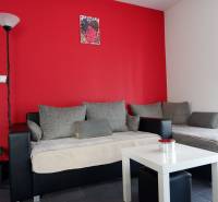 Interior of a family house with gray sofas, a red wall, and a white table.