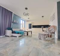 Living room with large windows and light tiles in a family house.