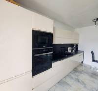A kitchen in a family house with a glossy countertop and built-in appliances, floor with a marble pattern.