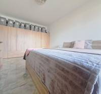 Bedroom in a family house with a double bed, wardrobe, and floor with wood decor.