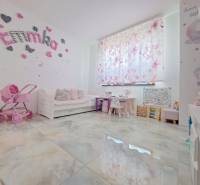 Children's room in a family house with decorations, a stroller, and desks. The floor has a wooden decor.