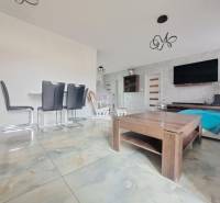 Interior of a family house with light tiles, modern furniture, and a wall with a television.