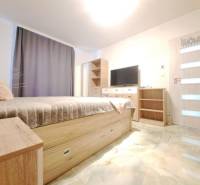 Bedroom in a family house with a bed, wardrobe, television, and floor with a wooden decor.