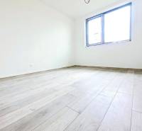 An empty room with a wooden floor and a large window in a family house.