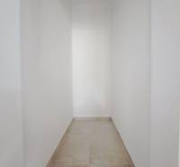 A narrow hallway in a family house with white walls and a light floor.