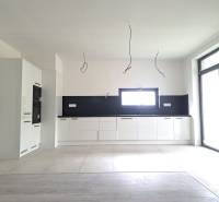 A kitchen in a family house with a wooden decor floor, white cabinets, and built-in appliances.