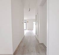 A hallway in a family house with a wooden decor floor and white walls.