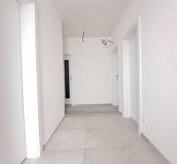 A bright hallway in a family house with white walls and light tiles.