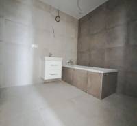 A bathroom in a family house with tiles and a bathtub on neutral flooring.