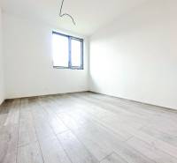 An empty room in a family house with a wood-patterned floor and a window.