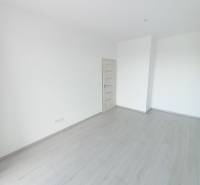 A room in a 2-bedroom apartment with white walls and a wood-patterned floor.