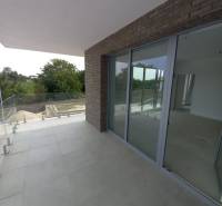 Balcony of a 2-room apartment in Galanta with tiles and glazing, surrounded by greenery.