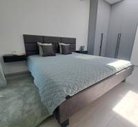 Bedroom with a large bed, gray wardrobes, and a black chandelier in a 2-room apartment.