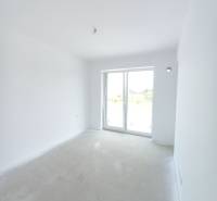 A bright room in a 2-room apartment with a large window and white walls.