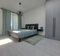 Bedroom in a 2-room apartment with wood-patterned flooring and sliding doors.