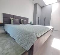 Bedroom in a 2-room apartment with light from a skylight and minimalist furnishings.