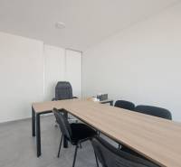 Office desks and black chairs in commercial spaces with a minimalist interior.